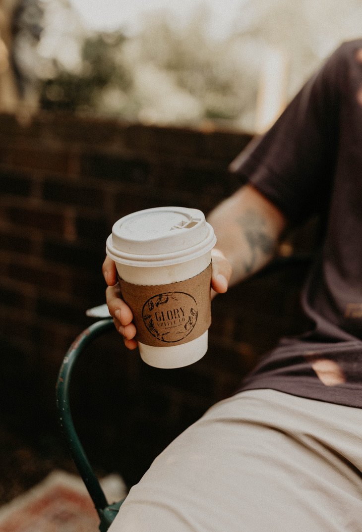 A guest holding a Glory Coffee takeaway cup